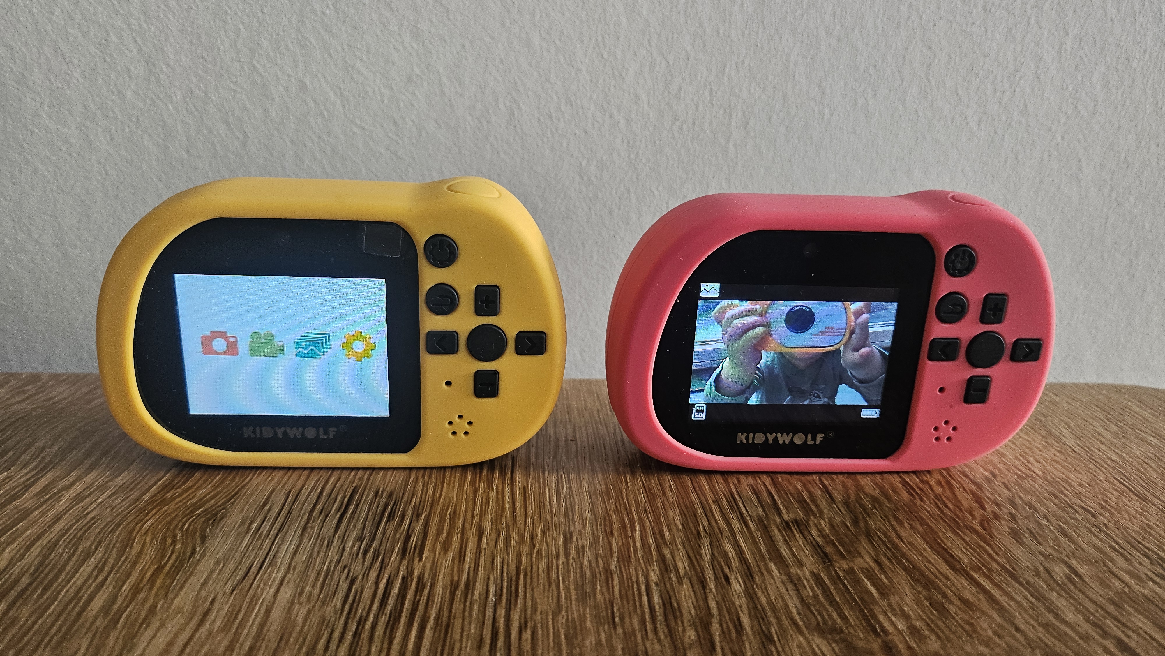 Twee Kidywolf Kidycams tijdens het thuis testen: de gele met het menu, de roze met een testfoto van de gele camera